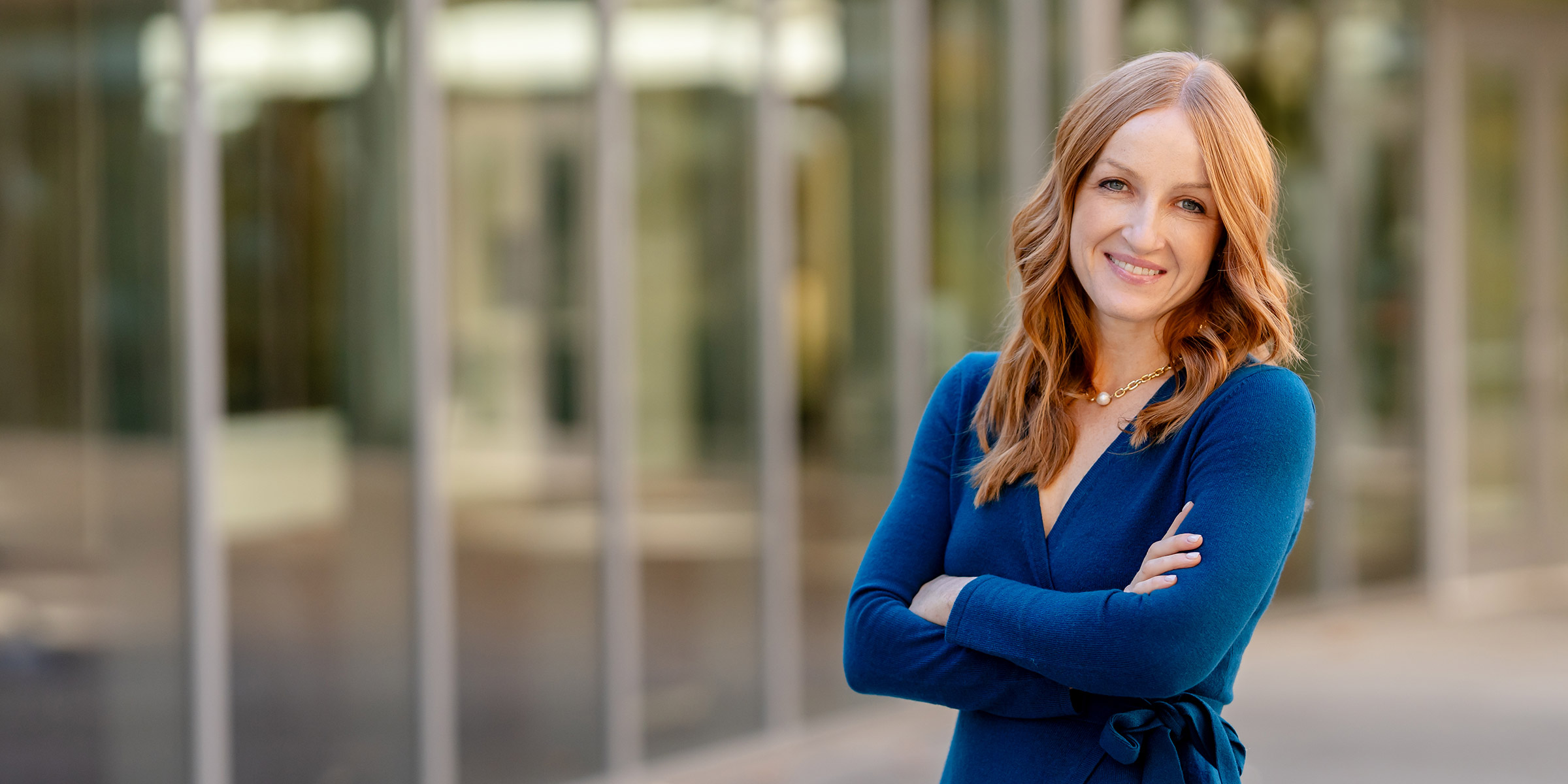 Vanessa Errecarte of Marketing Simplified standing in front of a panel of glass windows smiling with arms folded